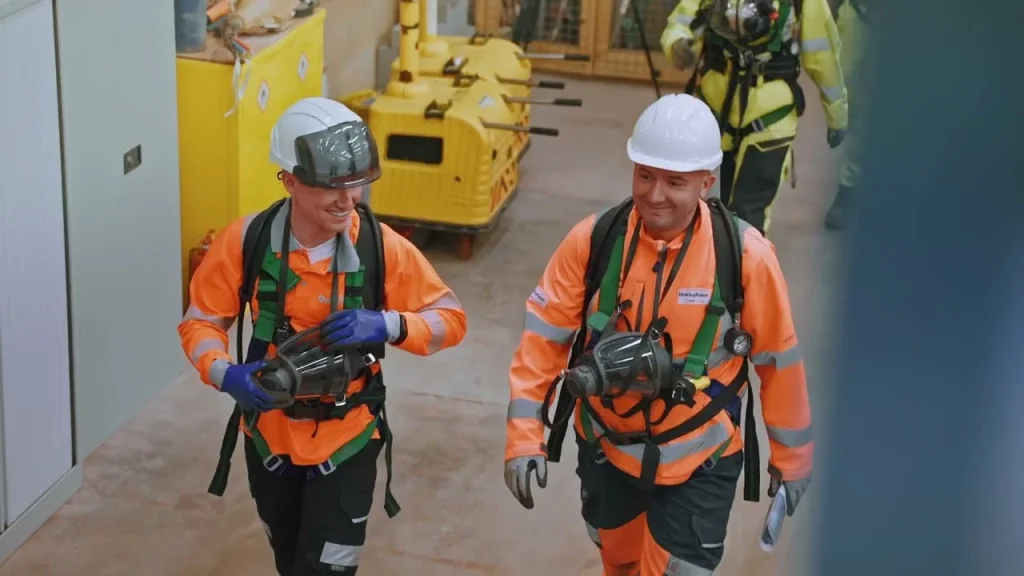 Film still of two trainees in harnesses on a confined space course