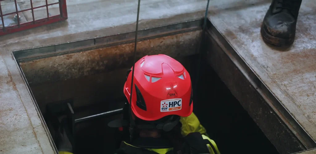 Delegate in a red helmet inside a confined space hatch