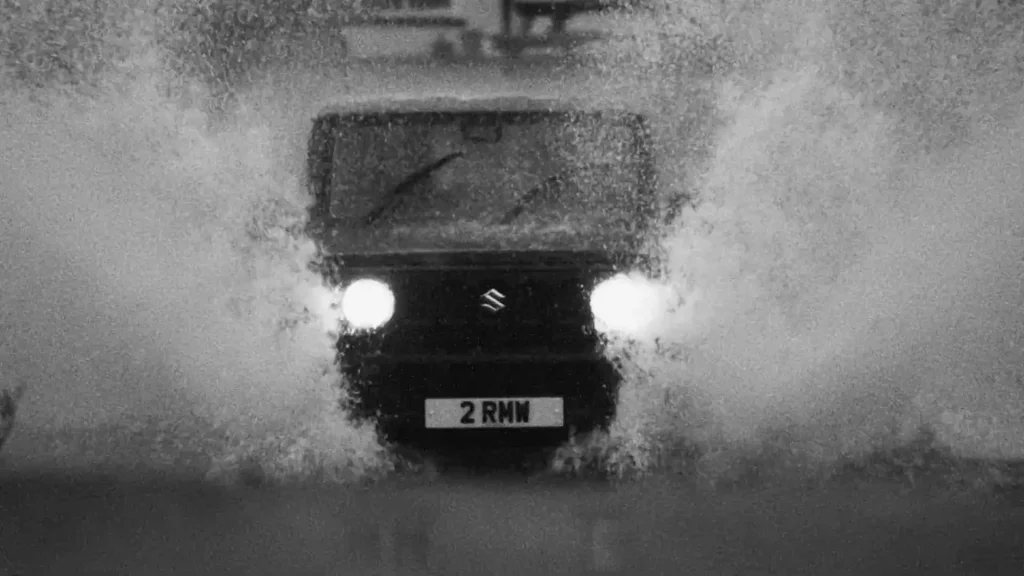 Suzuki Jimny driving through water with headlights on
